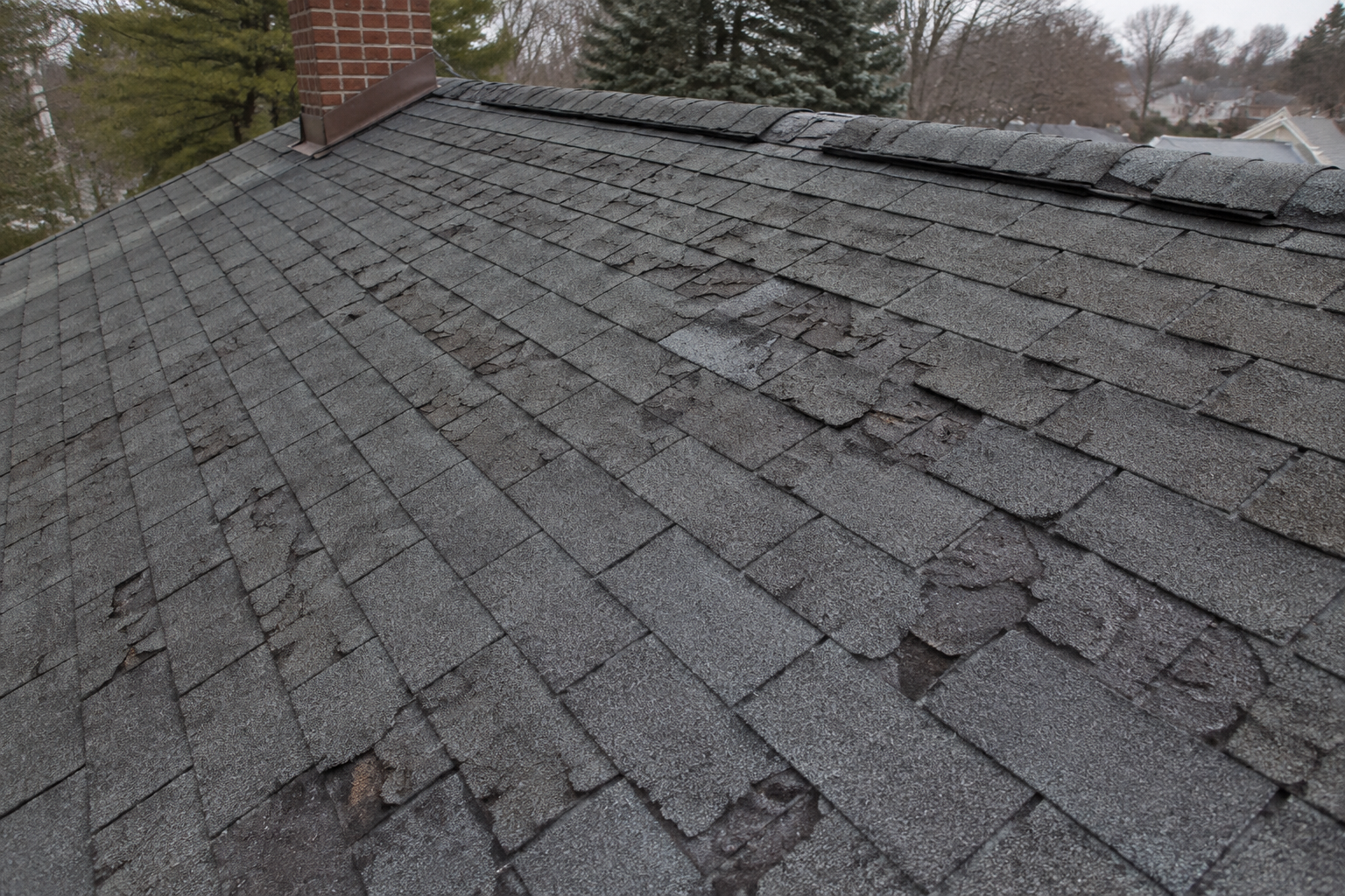 Worn asphalt-shingle roof with curling, cracking, granular loss and damaged ridge caps